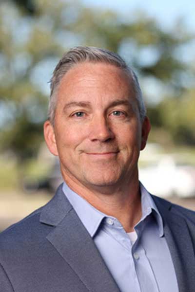 100825-ATCC-Portraits-0074-Exported-for-Web Headshot of man with blue-gray suit, blue eyes, and short gray hair