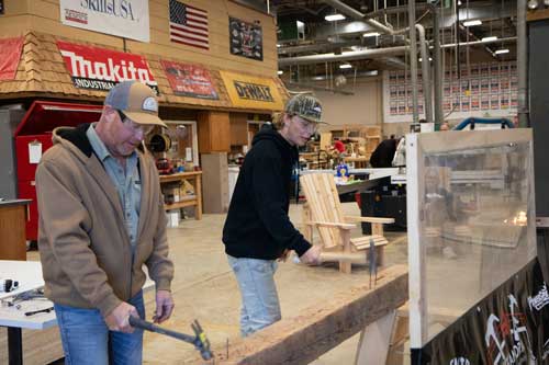 ATCC-Open-House-Fall2025_3087 Two men holding hammers attempting to hammer nails into a board
