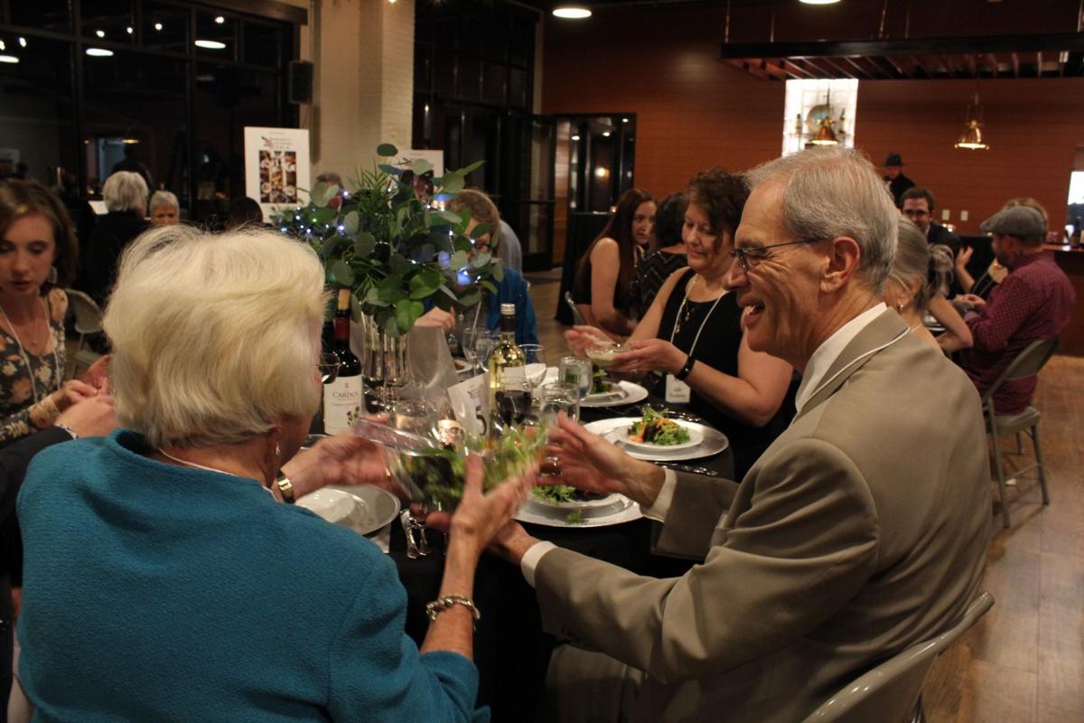 Dressed-up individuals sit at a round table with a white tablecloth, at the Believers & Achievers Gala