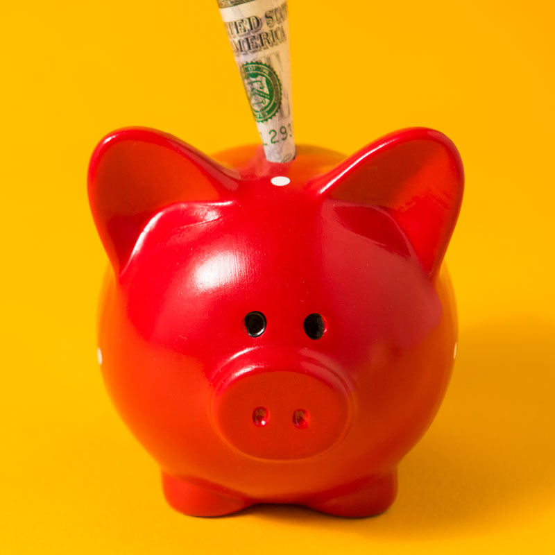 Red piggy bank with money sticking out the top